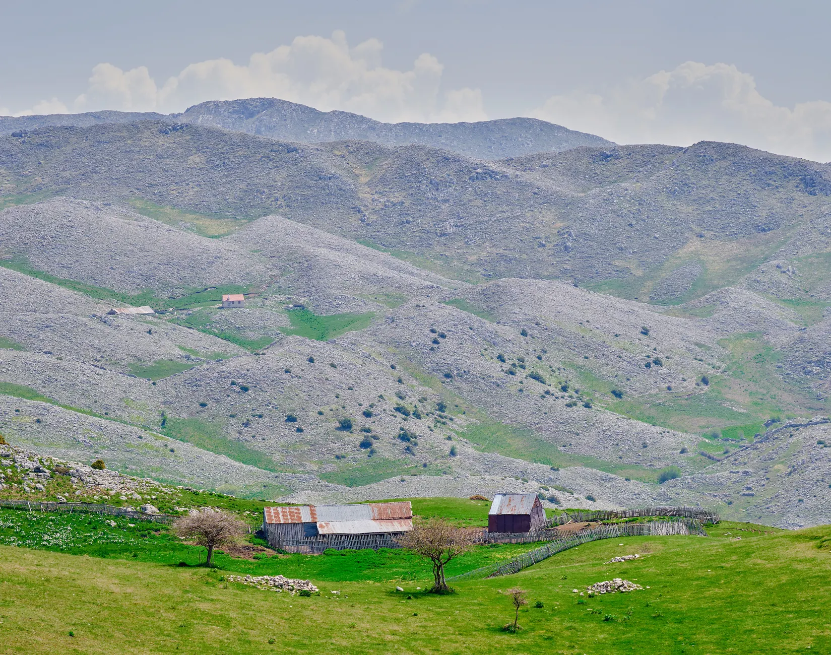 Scenic view of a rustic farmhouse nestled in Albania's rugged mountains.