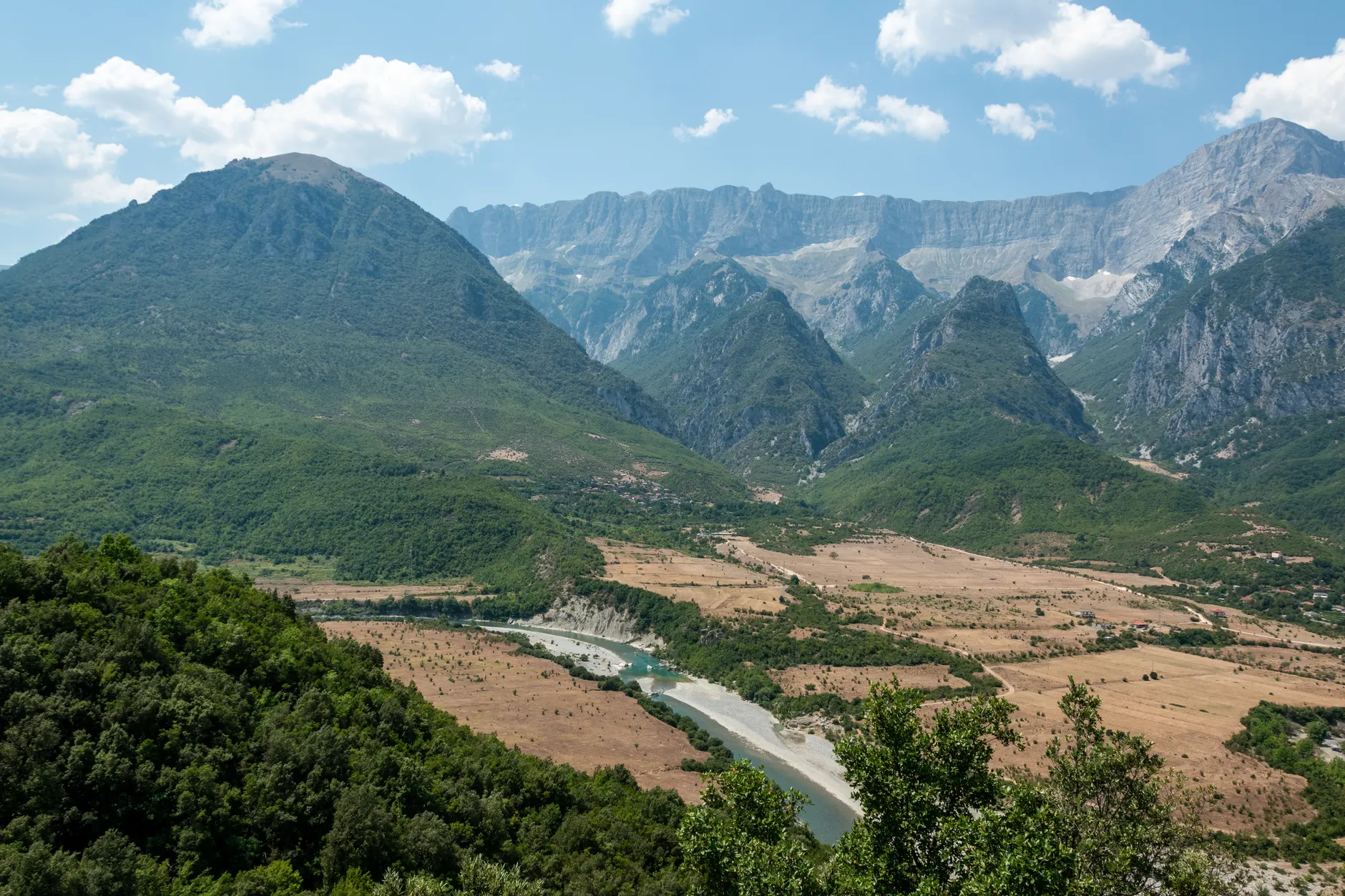 Aerial view of Përmet valley with lush greenery and majestic mountains in Albania.