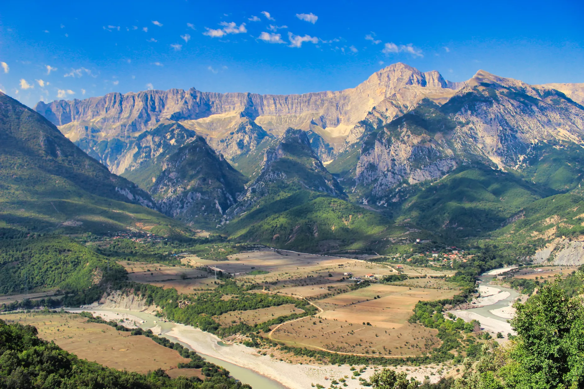 A breathtaking view of Albania's majestic mountains and serene river landscape.